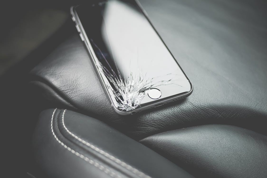 cracked and scratched iPhone sitting on leather seat