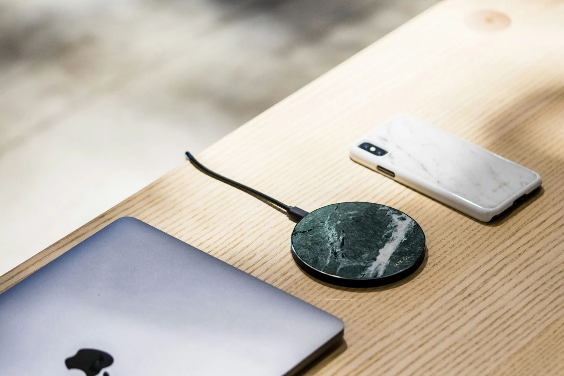 a desk with a wireless charger, a laptop, and a phone