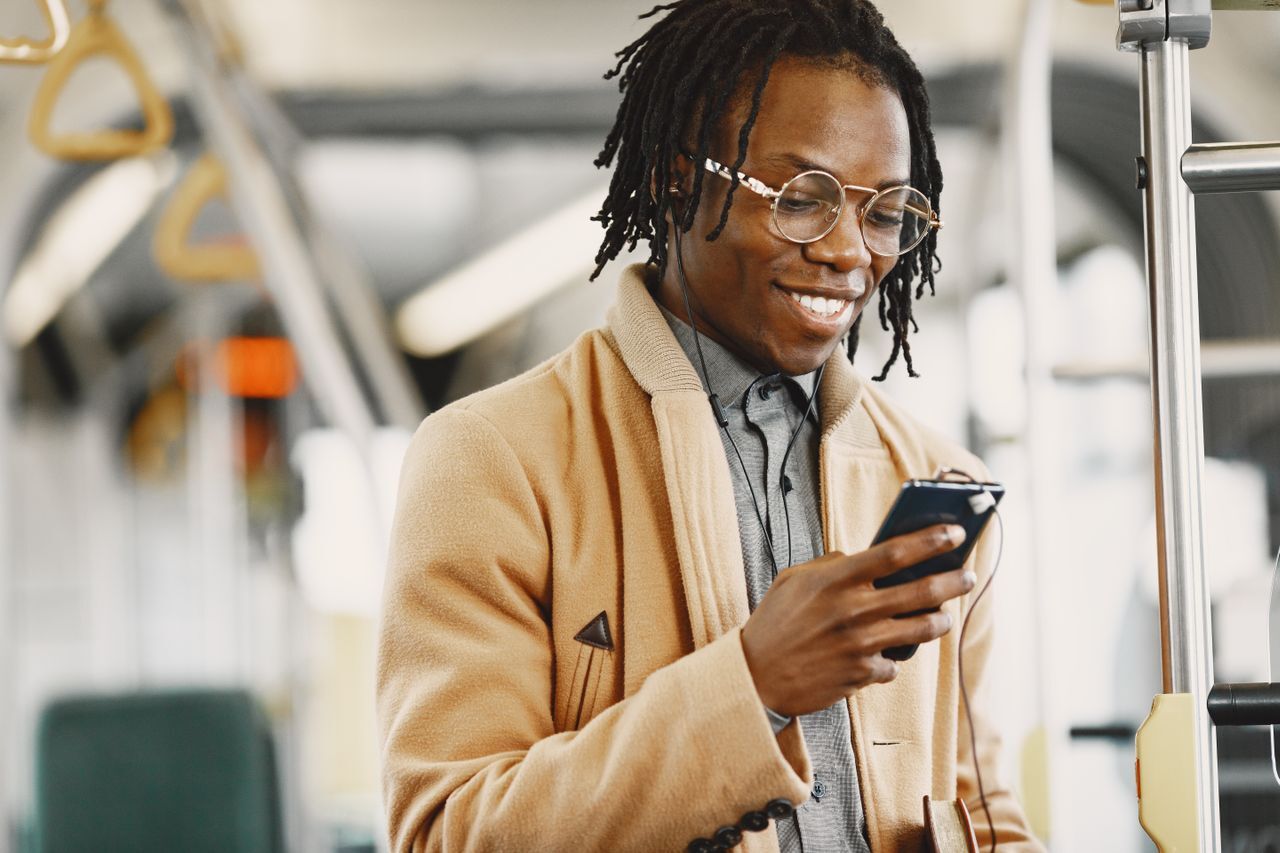 man smiling at phone on public transportation