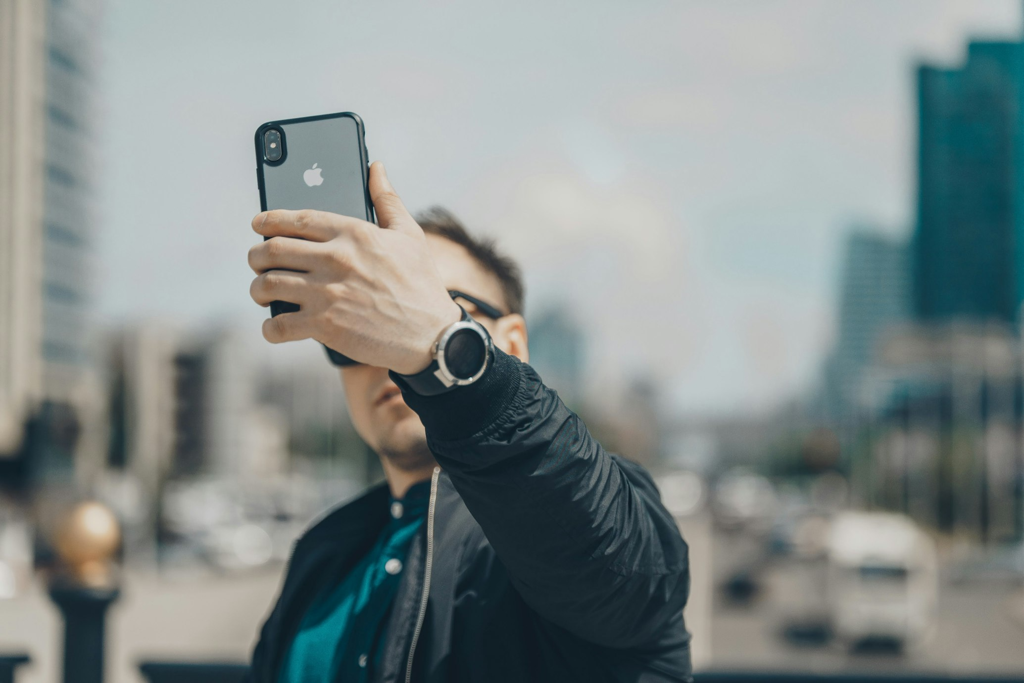 person taking a photo with iPhone in case in the city