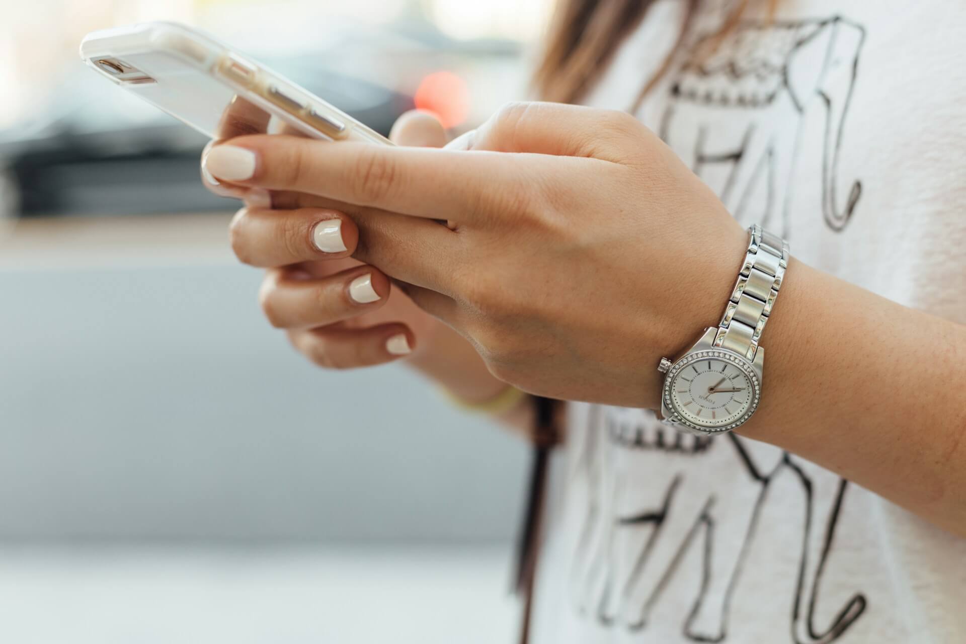 woman holding an iPhone on the sidewalk